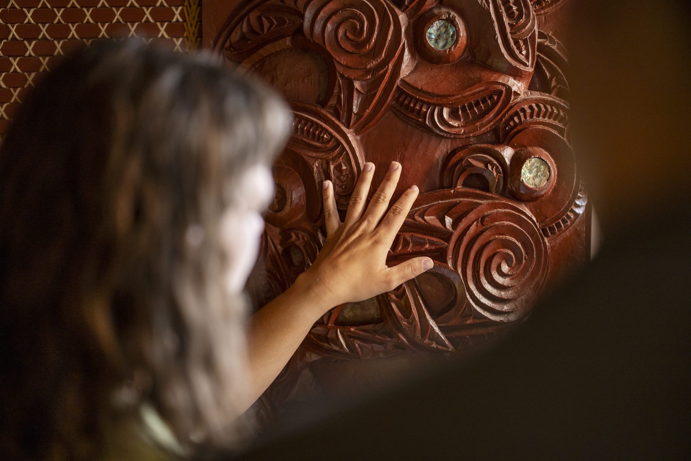 A child's hand tracing a carved Māori whakairo panel, Rotorua, Bay of Plenty